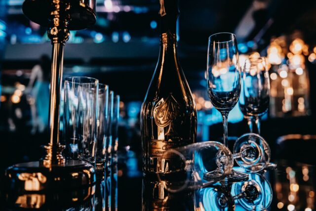 Gold champagne bottle with elegant glasses on a reflective surface, exuding luxury